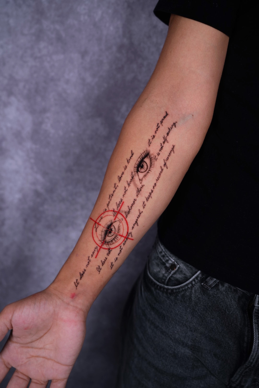 Realistic eyes with script lettering and red accents forearm tattoo by Camila