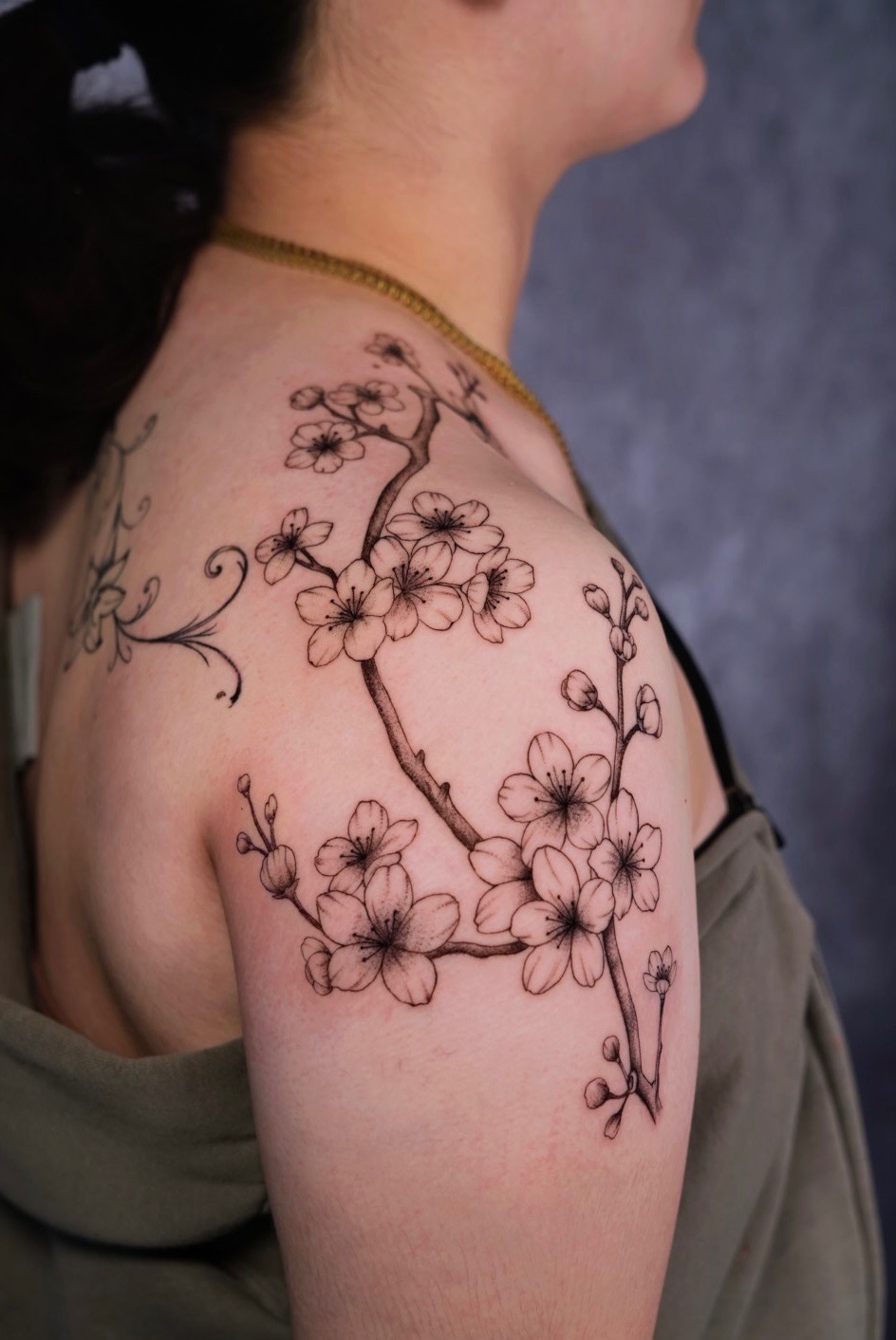 Fine line floral shoulder tattoo with script by Camila