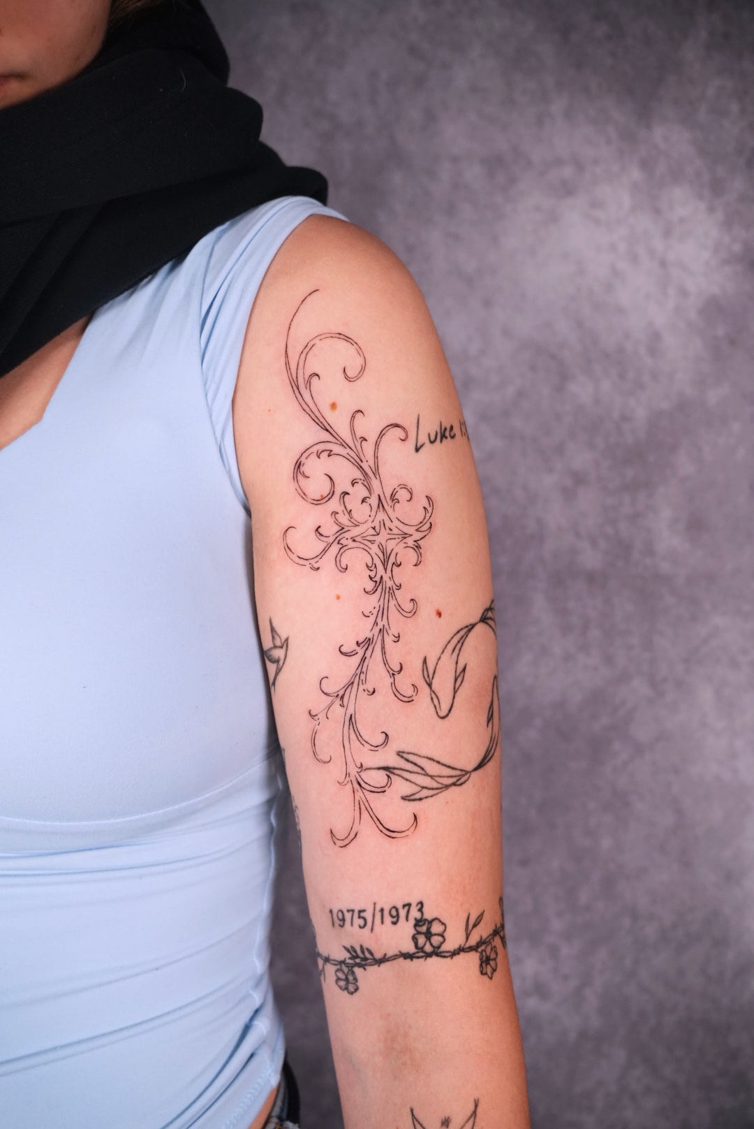 Ornamental upper arm tattoo with script and florals by Camila