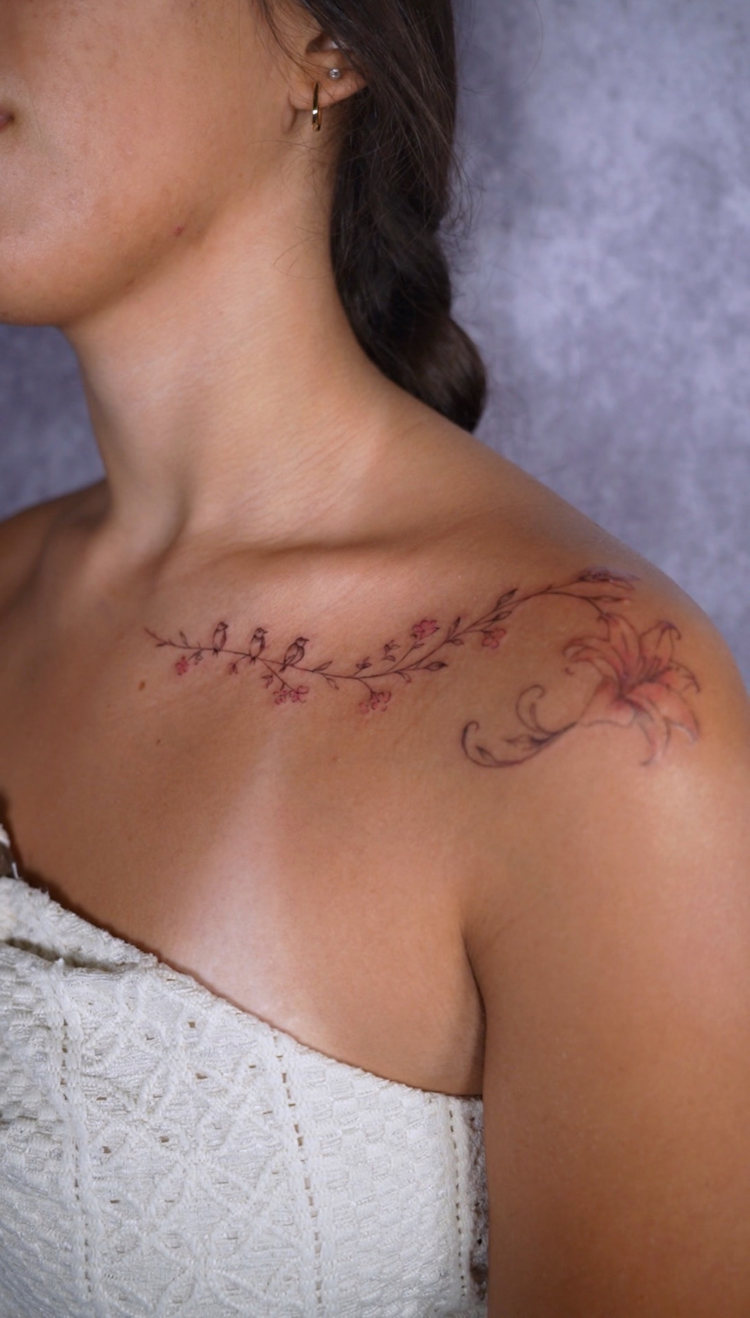 Delicate fine line branch and flower collarbone tattoo by Camila