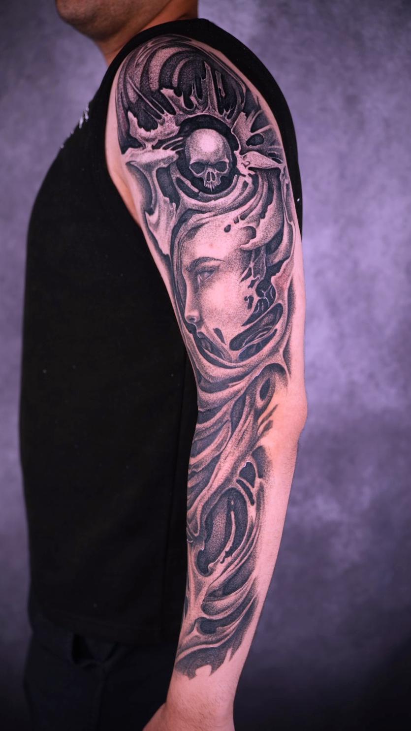 Black and grey skull and portrait sleeve tattoo by Eduardo Marquez