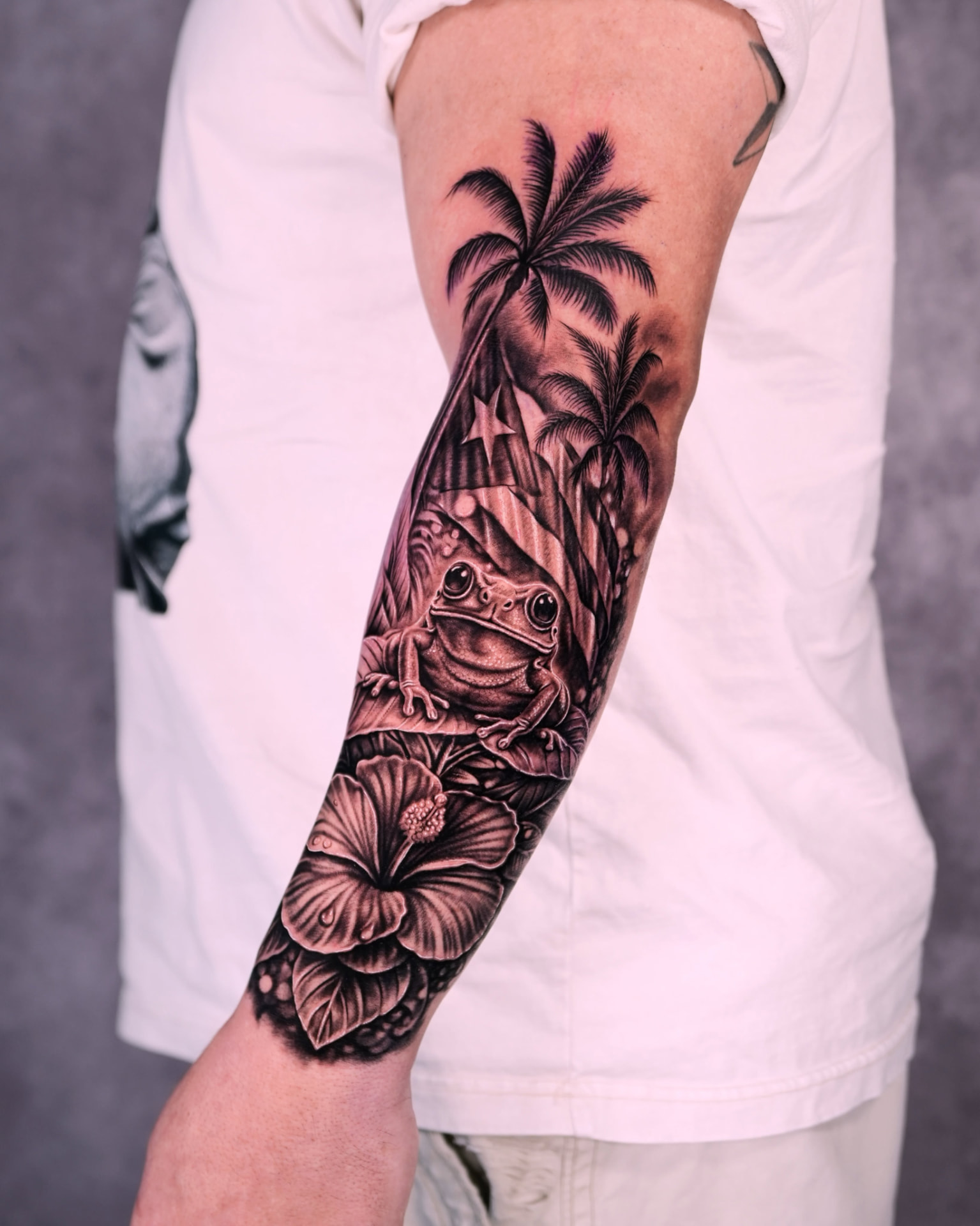 Black and grey realism frog, palm trees and hibiscus sleeve tattoo by Lions Ink