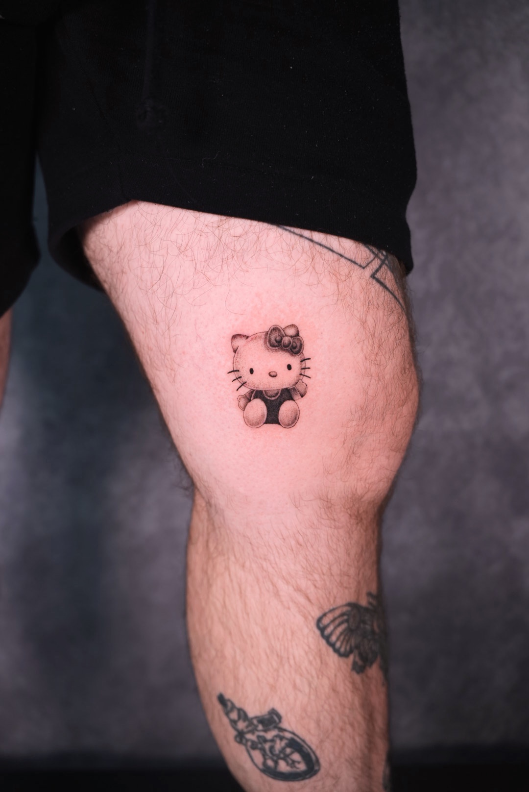 Small fine line Hello Kitty tattoo by Camila at Lions Ink